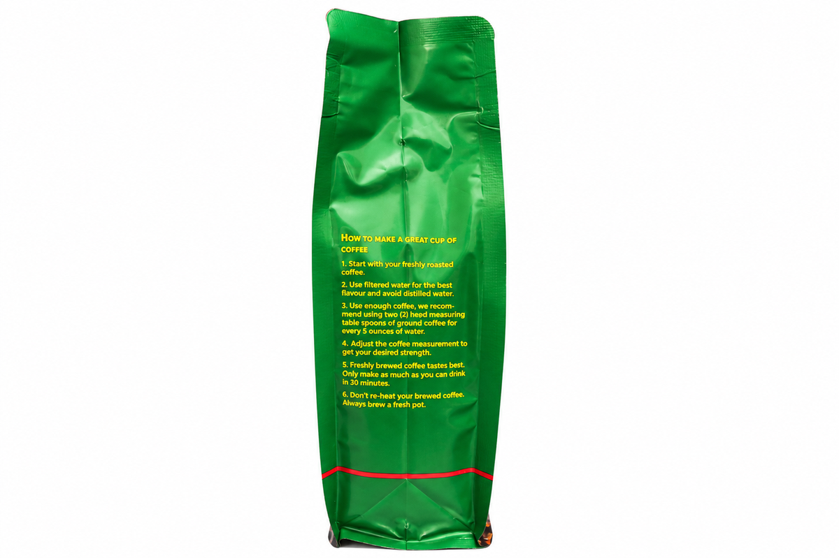 A green bag of coffee stands upright against a plain white background, showing printed instructions on the front in yellow and white text. Gibsons Kenyan coffee beans in whole bean form, 400g dark roast made from 100% Arabica coffee from Kenya