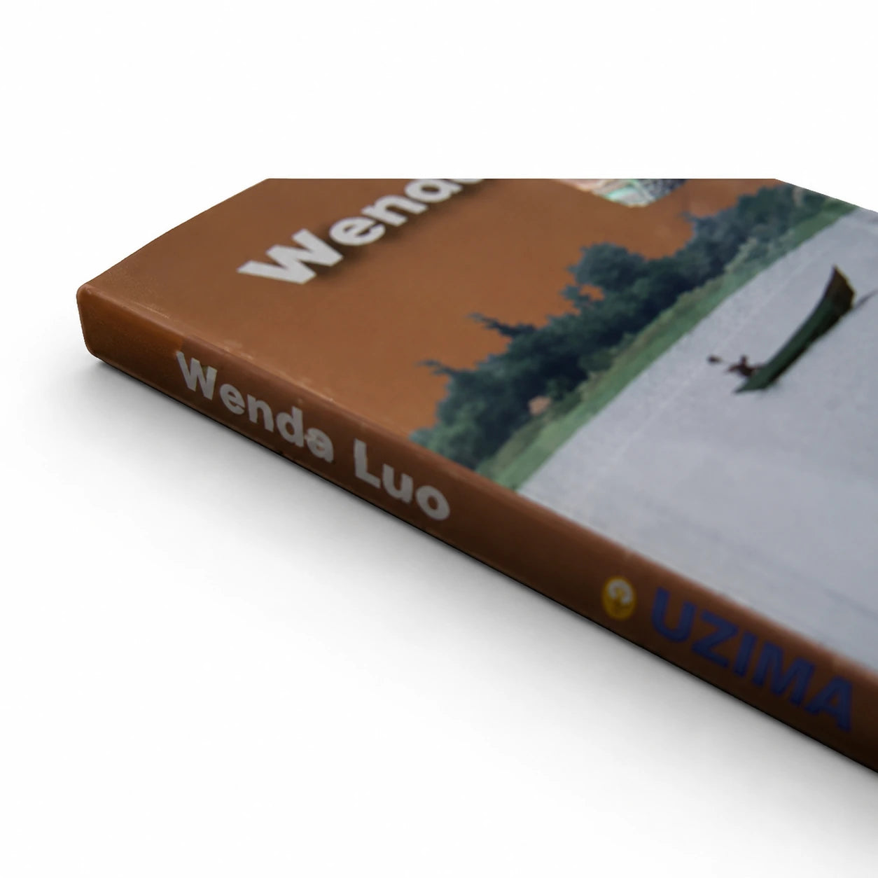 Wende Luo Dholuo Hymnal book by Wende Luo, shown at an angled close-up with its brown-orange cover, river scene, canoe, and blue UZIMA spine lettering.
